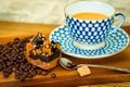 Exposition of caramel pie near white cup of coffee with sugar and coffee beans on wooden table and white brick wall background. Royalty Free Stock Photo