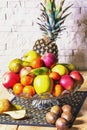 Exposition of fresh fruits, pineapple, green and red apple, kiwi, mandarin, pear on wooden table and white brick wall background, Royalty Free Stock Photo