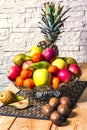 Exposition of fresh fruits, pineapple, green and red apple, kiwi, mandarin, pear on wooden table and white brick wall background, Royalty Free Stock Photo