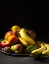 Exposition of fresh organic fruits on plate, orange, mango, banana, apple, kiwi, lemon on black background. Nature and healthy fru Royalty Free Stock Photo