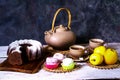 Exposition of hand made clay set on white wooden table and dark background, with tasty chocolate cake, marshmallows . Tea cup and