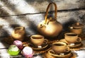 Exposition of hand made clay set on white wooden table with tasty marshmallow and green apple. Tea cup and clay kettle.