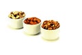 Exposition of porcelain bowl with nuts, pelled almonds, pistachios nuts and walnuts on white background.