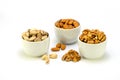 Exposition of porcelain bowl with nuts, pelled almonds, pistachios nuts and walnuts on white background.