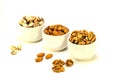 Exposition of porcelain bowl with nuts, pelled almonds, pistachios nuts and walnuts on white background.