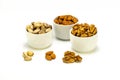 Exposition of porcelain bowl with nuts, pelled almonds, pistachios nuts and walnuts on white background.