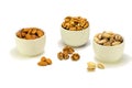 Exposition of porcelain bowl with nuts, pelled almonds, pistachios nuts and walnuts on white background.