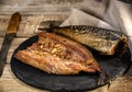 Exposition of smoked fish on wooden table. Tasty smoked fish with garlic, lemon, pepper.