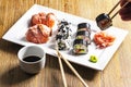 Exposition of sushi rolls on white plate, soya sauce, vasabi and sushi roll.