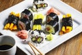 Exposition of sushi rolls on white plate, soya sauce, vasabi and sushi roll.