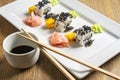 Exposition of sushi rolls on white plate, soya sauce, vasabi and sushi roll.