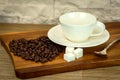 Exposition of white cup of coffee with sugar and coffee beans on wooden table and white brick wall background. Royalty Free Stock Photo