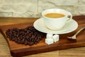 Exposition of white cup of coffee with sugar and coffee beans on wooden table and white brick wall background. Royalty Free Stock Photo