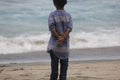 the expression of a child dressed in a blue striped shirt who is enjoying the beach view and wants to play in the sand