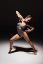 Dynamic portrait of young flexible contemp dancer dancing isolated on dark studio background in spotlight. Art, beauty