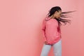Studio shot of young excited girl with afro hairdo in casual style outfit having fun isolated on pink background Royalty Free Stock Photo
