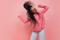 Studio shot of young excited girl with afro hairdo in casual style outfit having fun isolated on pink background Royalty Free Stock Photo