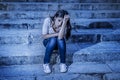 Expressionist edited portrait of young sad and depressed woman or teen girl sitting lonely at street staircase looking desperate a Royalty Free Stock Photo