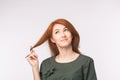 Expressions and people concept - Portrait of a beautiful young woman with red hair thinking over white background Royalty Free Stock Photo