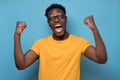 Expressive african american man celebrating success raising his fists up