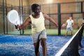 Expressive african american man playing paddle tennis on indoor court