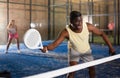 Expressive african american playing paddle ball on closed court