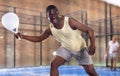 Expressive african american playing paddle ball on closed court