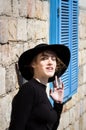 Expressive beautiful young woman in black with black hat looking