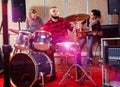 Expressive drummer with his bandmates practicing in rehearsal ro Royalty Free Stock Photo