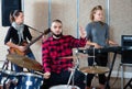 Expressive drummer with his bandmates practicing in rehearsal room Royalty Free Stock Photo