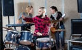 Expressive drummer with his bandmates practicing in rehearsal room Royalty Free Stock Photo