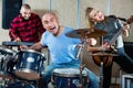 Expressive drummer with his bandmates practicing in rehearsal room Royalty Free Stock Photo