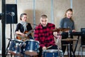 Expressive drummer with his bandmates practicing in rehearsal room Royalty Free Stock Photo