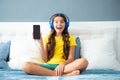 Expressive emotional excited teen girl showing screen phone. Teenager child girl wearing headphones listening music on