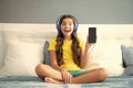 Expressive emotional excited teen girl showing screen phone. Teenager child girl wearing headphones listening music on