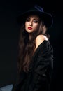 Expressive female model posing in black shirt and elegant hat wi Royalty Free Stock Photo