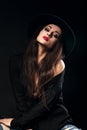 Expressive female model posing in black shirt and elegant hat wi