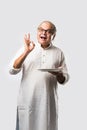 Expressive Indian Old man eating food from empty or blank white plate or bowl Royalty Free Stock Photo