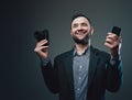 Expressive man dressed in custom suit holding phone and photo camera Royalty Free Stock Photo