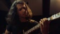 Expressive man playing guitar in studio. Guitarist gesticulating in hall.