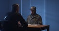 Expressive policeman examining military man in interview room