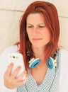 Expressive portrait of a pretty red-haired woman reading the information with annoyance on her mobile phone