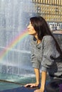 Expressive production figures. girl with bright makeup brunette with long hair in a gray lace sweater Spray Rainbow water fountain