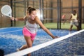 Expressive resolved girl playing paddle ball on closed court