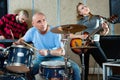 Expressive drummer with his bandmates practicing in rehearsal room Royalty Free Stock Photo