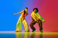 Expressive, talented, artistic young man and woman, hip hop dancers in motion, performing against blue red background in