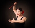 Expressive woman dance flamenco under dramatic light. Attractive lady with red rose in hair and in black dress hold a Royalty Free Stock Photo