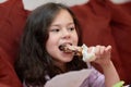 expressive young girl is eating chicken and vegetables for dinner on the couch while watching cartoons Royalty Free Stock Photo