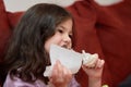 expressive young girl is eating chicken and vegetables for dinner on the couch while watching cartoons Royalty Free Stock Photo