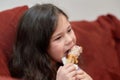 expressive young girl is eating chicken and vegetables for dinner on the couch while watching cartoons Royalty Free Stock Photo